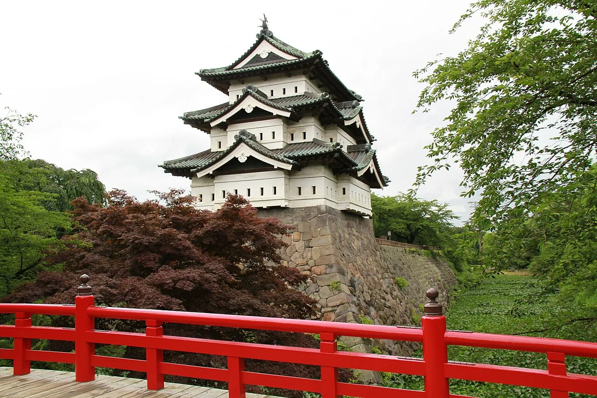 Hirosaki Castle keep beyond a red bridge, in its position at the time of the photograph