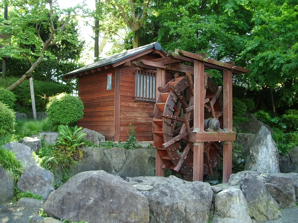 緑の木々と岩に囲まれた林試の森公園の木造の水車